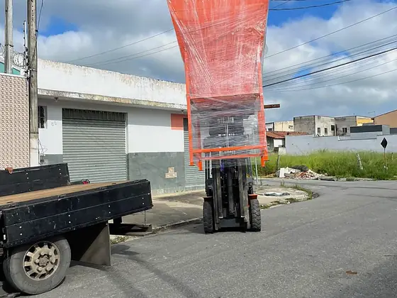 Prensa embalada sendo movimentada por empilhadeira na expedição